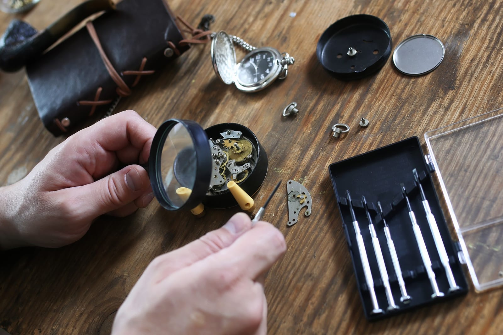 Lente d'ingrandimento e set di cacciaviti da orologiaio su un banco in legno